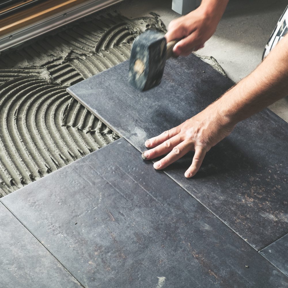 Worker placing ceramic floor tiles Worker carefully placing ceramic floor tiles on adhesive surface